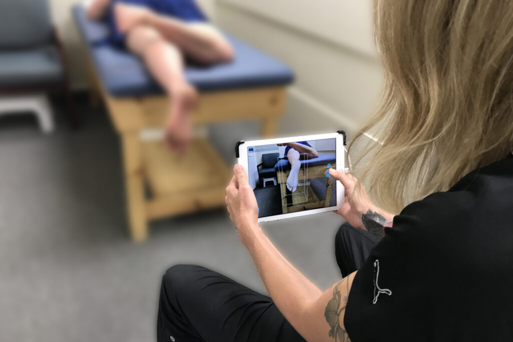 A clinician using a tablet application to take a digital 3D scan of a patient's foot for custom orthotics.