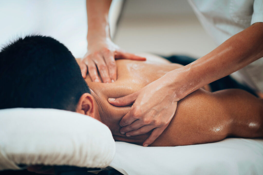 Physical therapist doing massage of male's shoulder