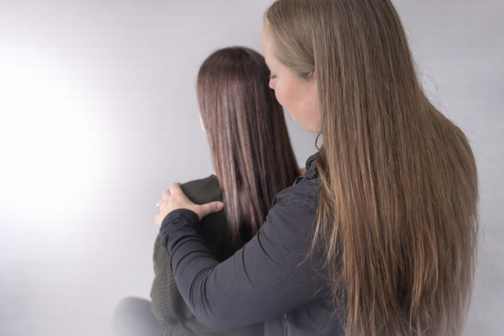 A female physiotherapist performing a hands-on shoulder and posture assessment on a patient.