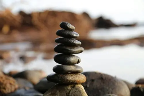 A perfectly balanced stack of smooth dark zen stones on a rocky beach, symbolizing natural health and wellness.
